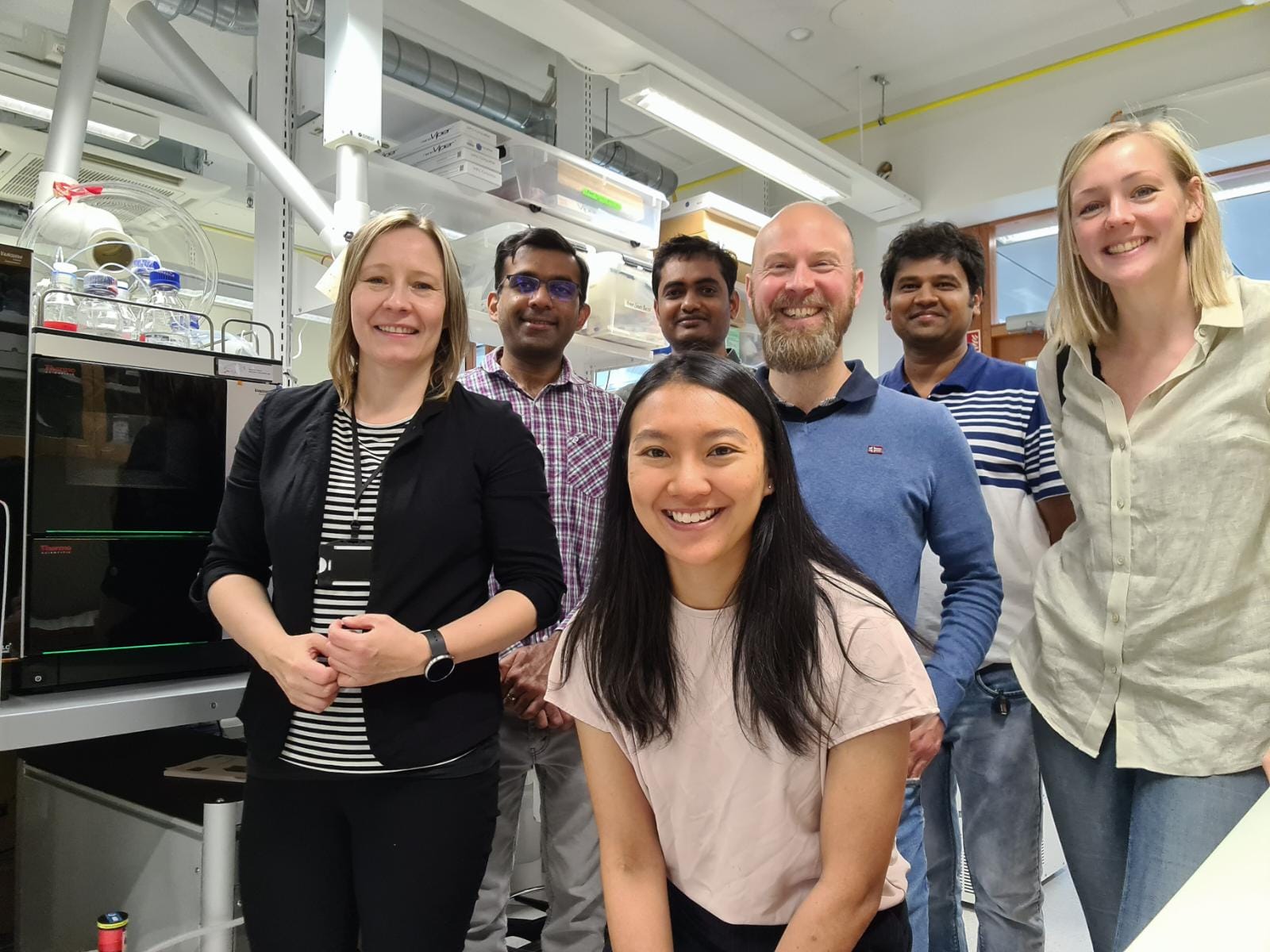 Seven people from both MIMS and FIMM standing in a lab