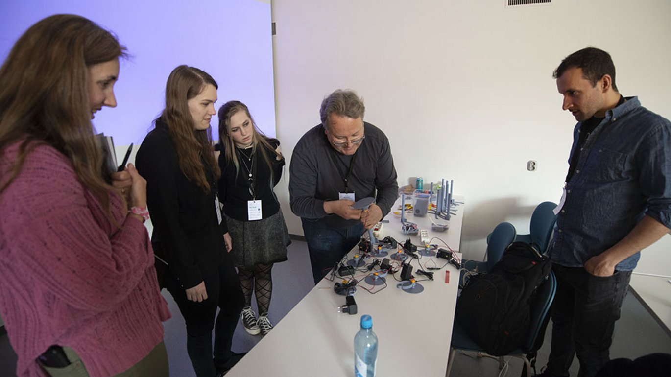 Five people in a lab looking at microscopy equipment on a table