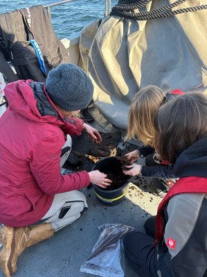 Scientists studying a peat sample onboard a research vessel