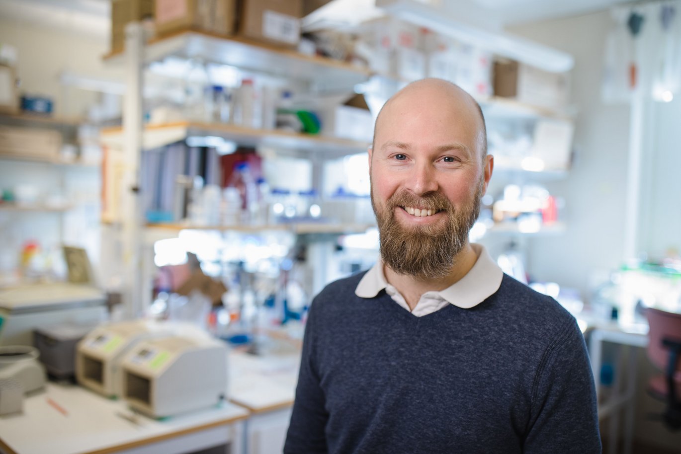 Dr. Schröder wearing a dark blue sweater and standing in a laboratory