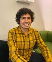 Jaime Castro-Mondragón in a yellow shirt sitting on a sofa