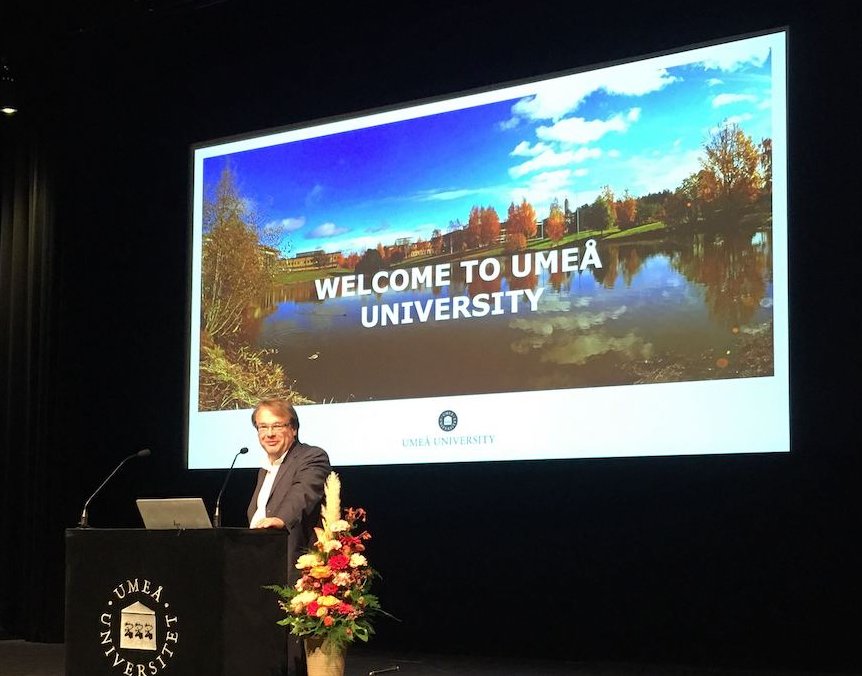 Oliver Billker at a lecturn with a a slide of Umeå University in the background