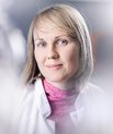 Emma in a white lab coat and pink top with a blurred background
