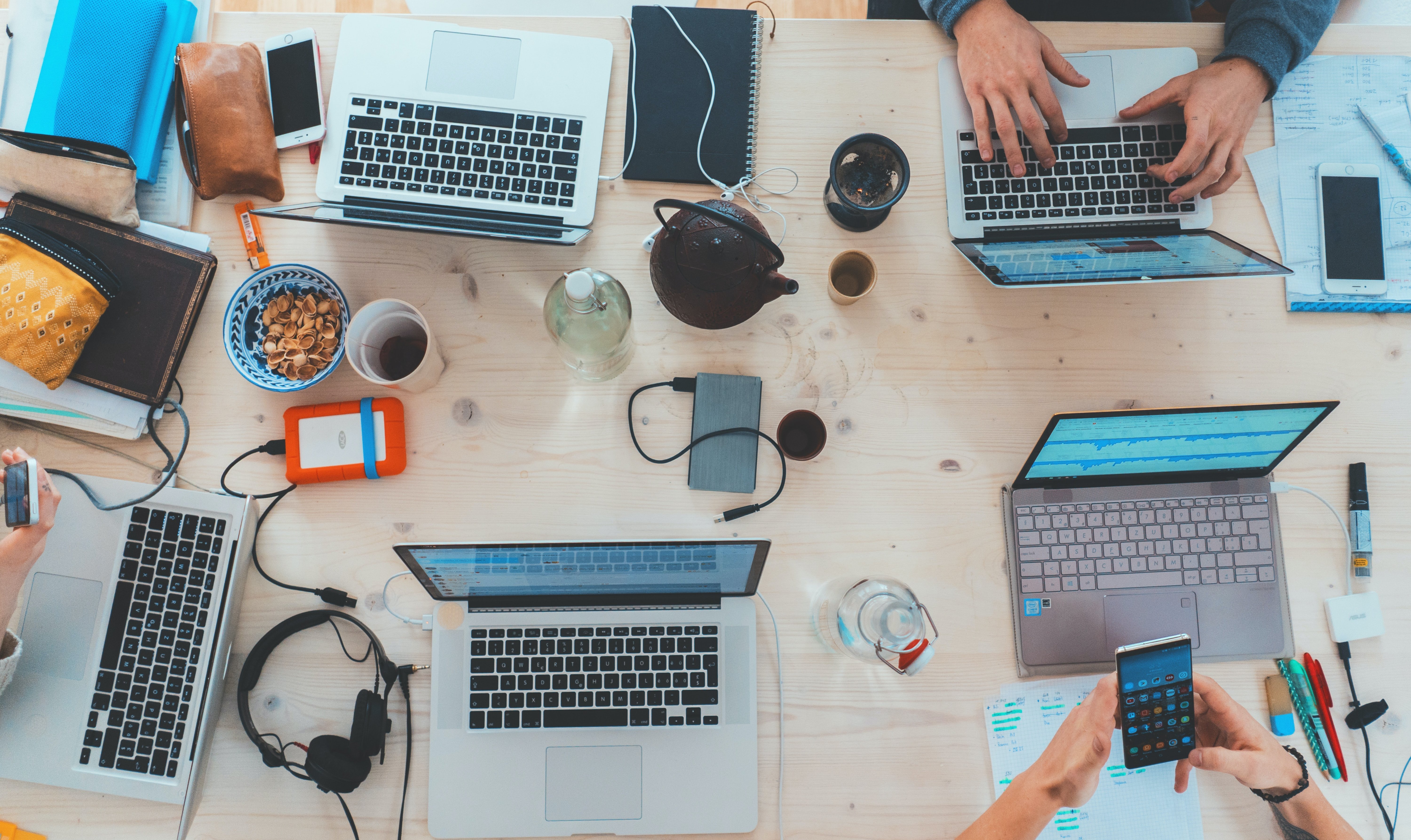  People sitting down near table with assorted laptop computers