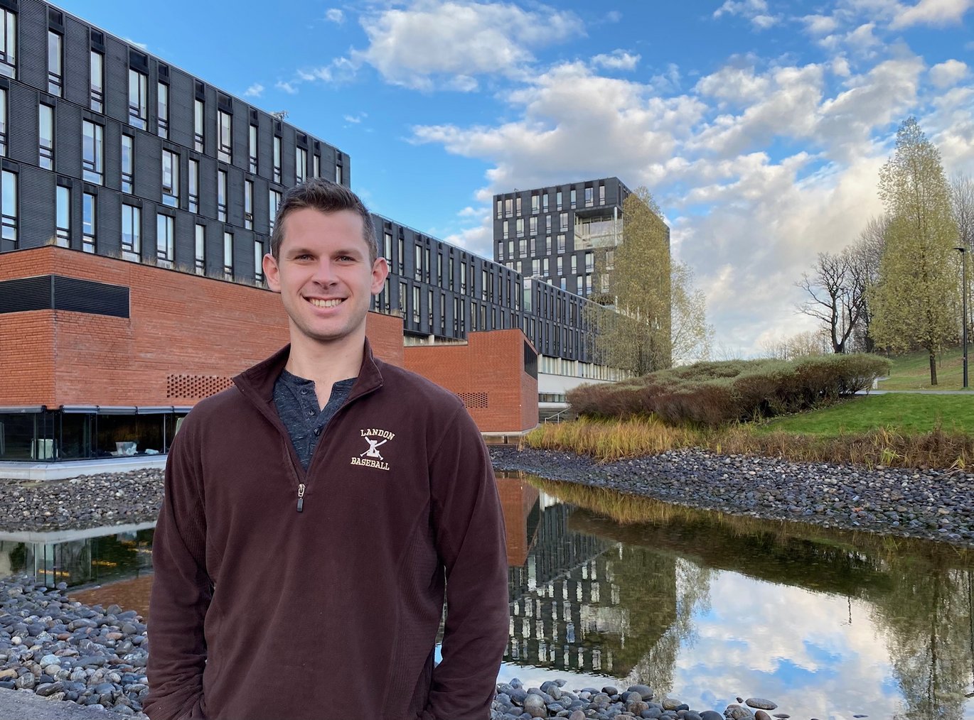 Alex Harvey in a burgandy sweater with research buildings in background.