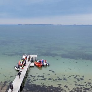 Photo towards the beach and sea, showing divers and diving boat getting ready to dive