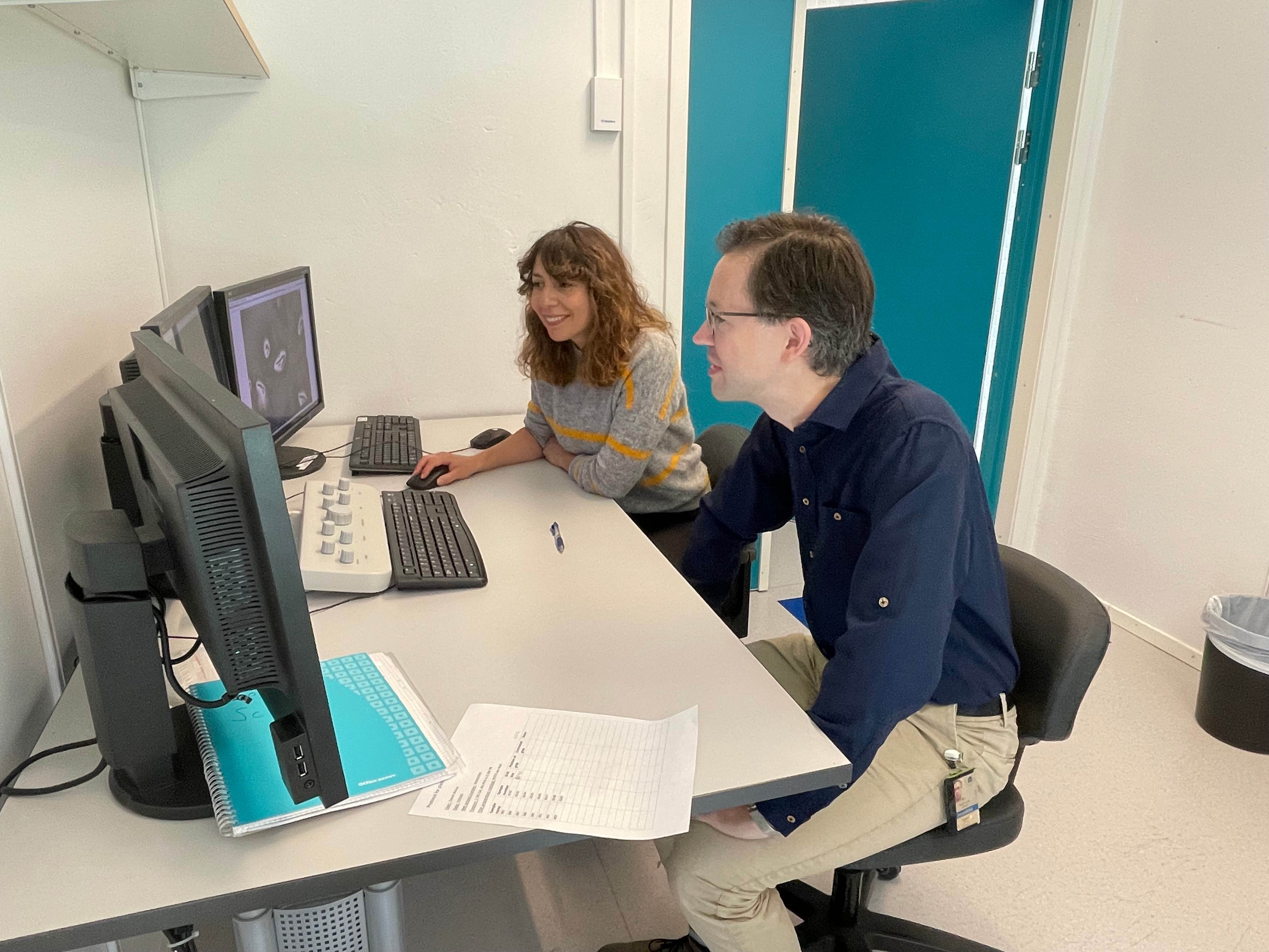 Two researchers at a desk looking at computer screens