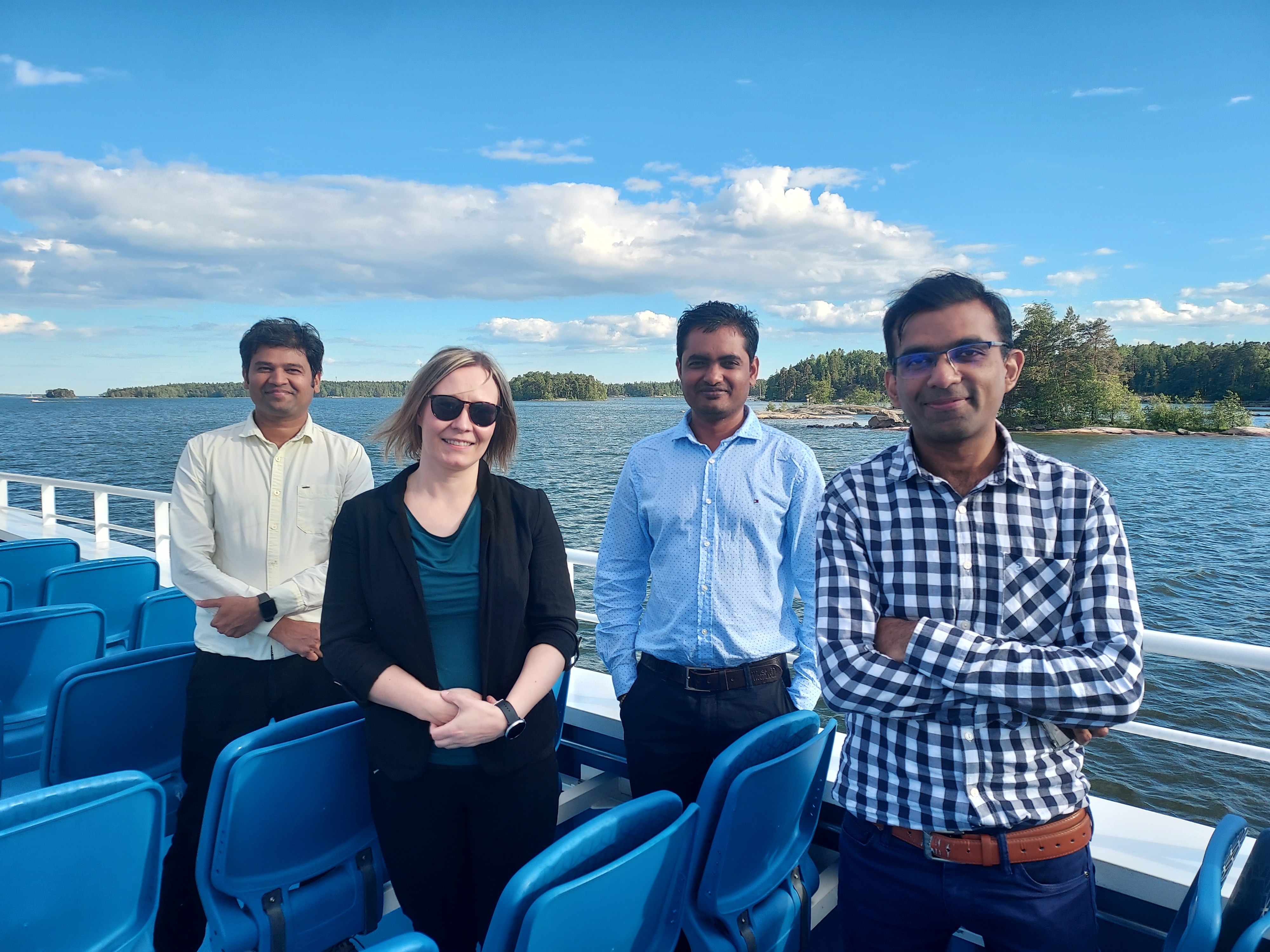 Four people standing on a small cruise boat in the Helsinki archipelago