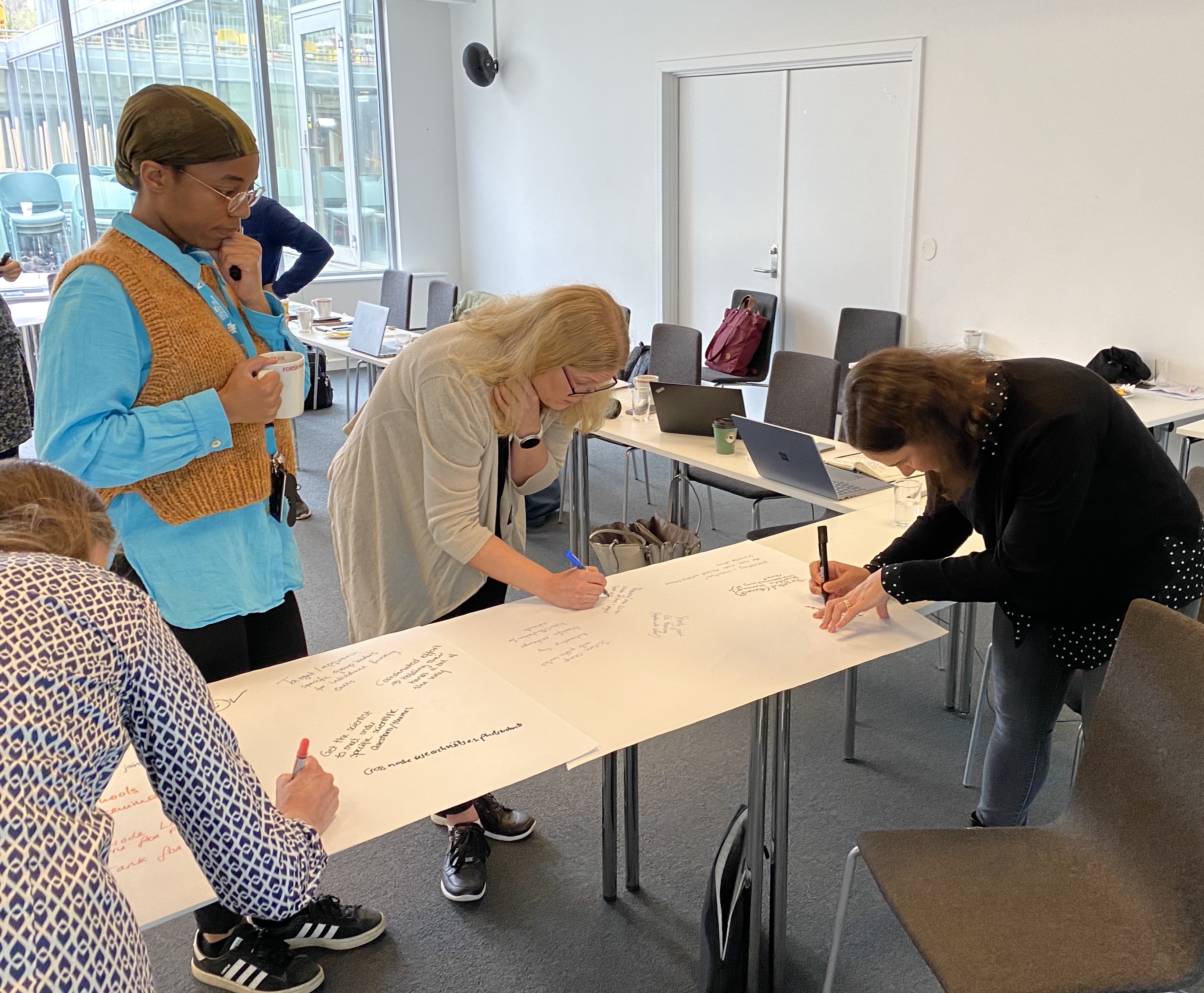 People writing on a large sheet of paper on a table