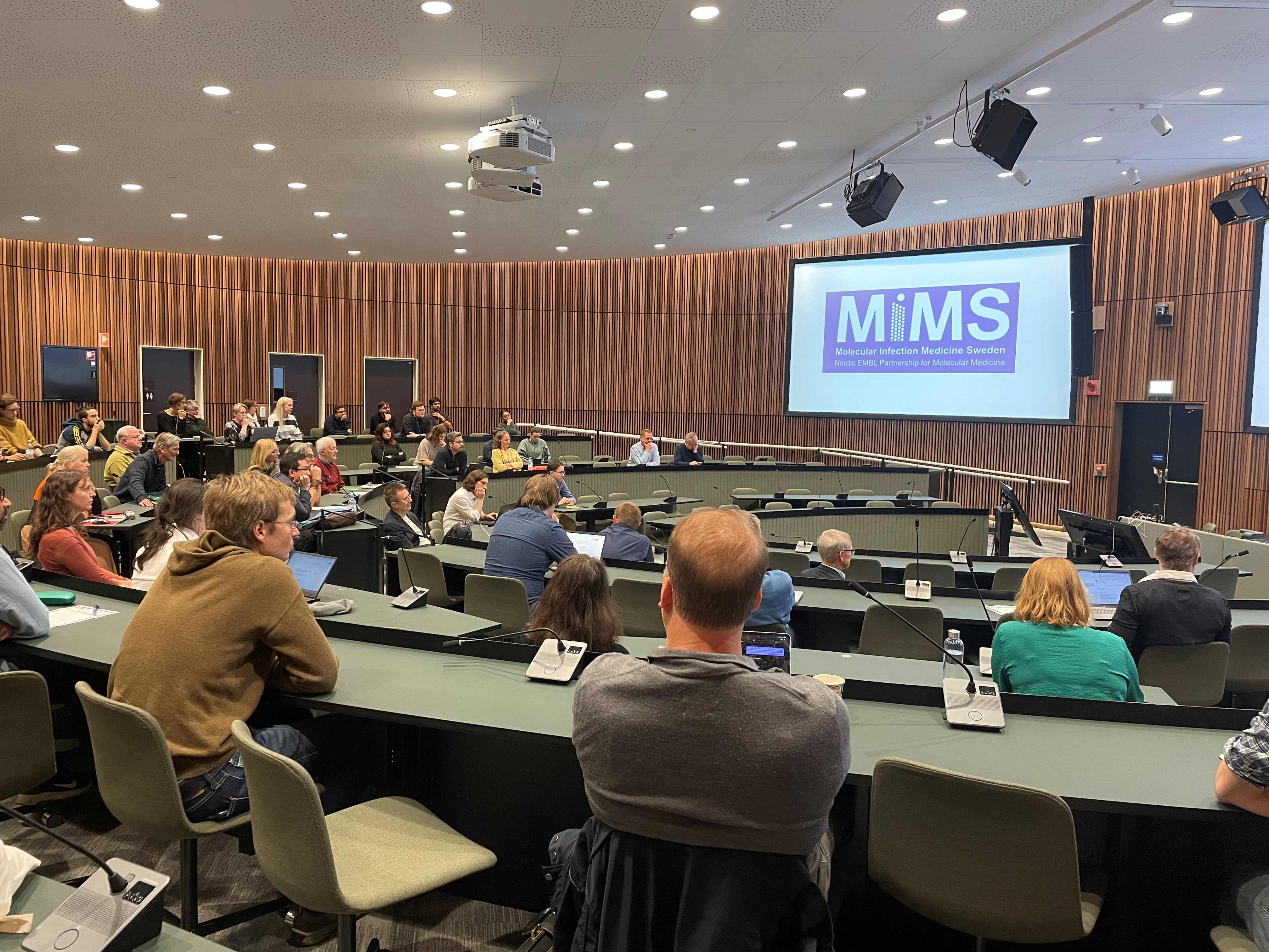 a lecture hall with people looking at the screen