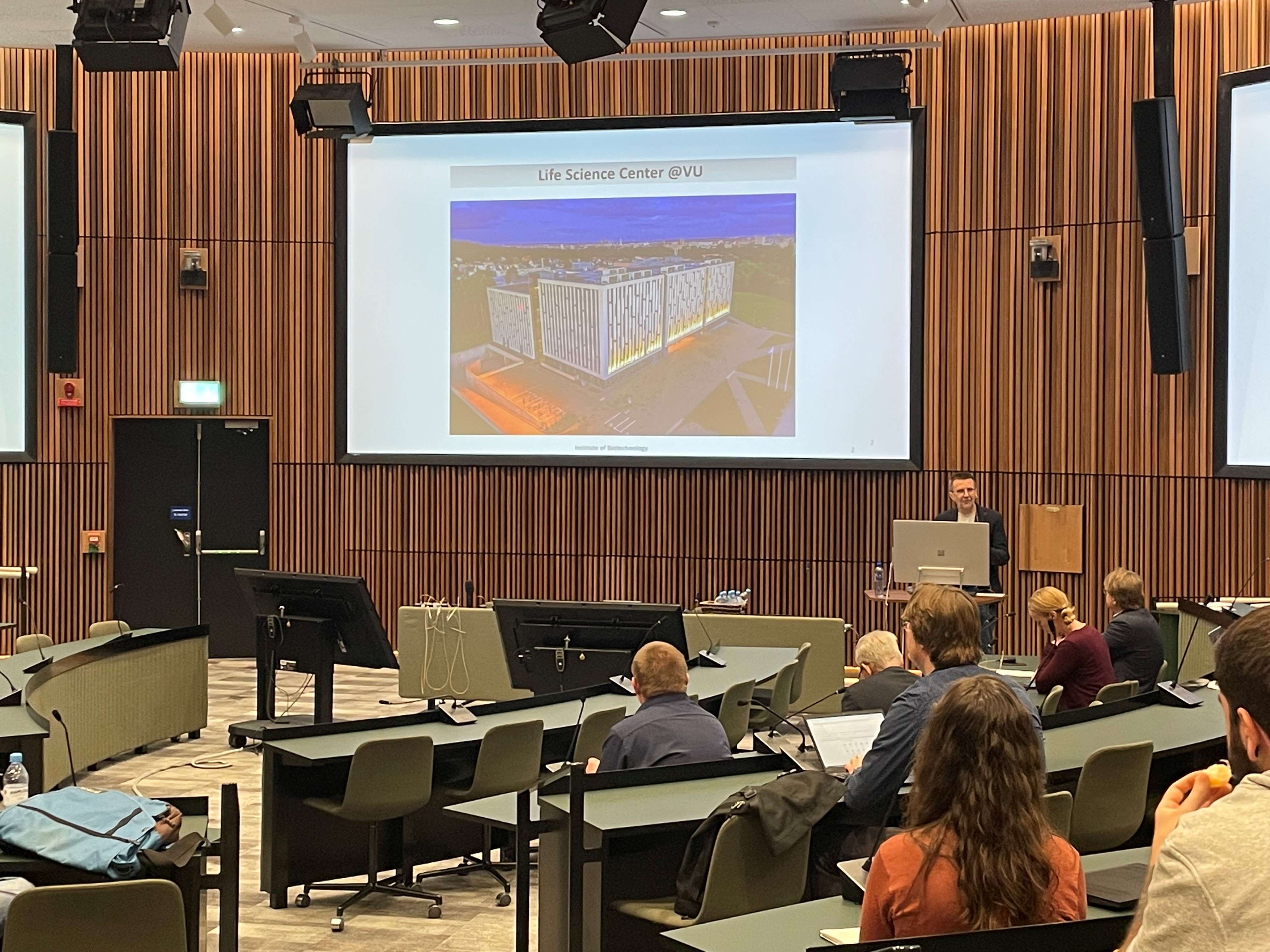 a lecture hall with Prof. Virginijus Šikšnys at the podium