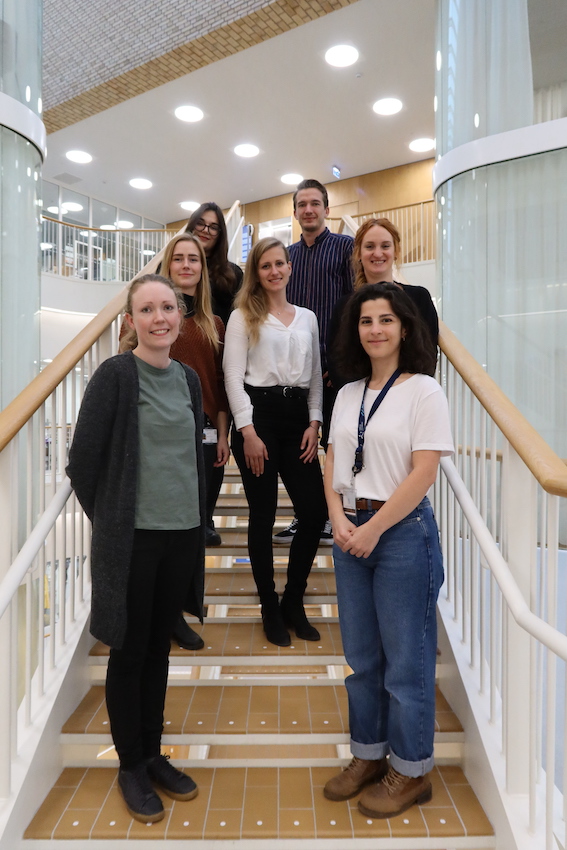 6 women and 5 men standing on stairs in a research center